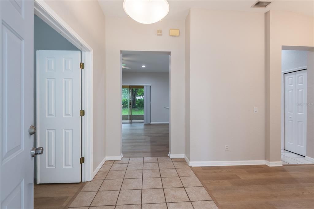 An entryway with tiled flooring leads to a living area with wood-look floors and sliding doors — 11112 HOLLY CONE DRIVE, RIVERVIEW, FL