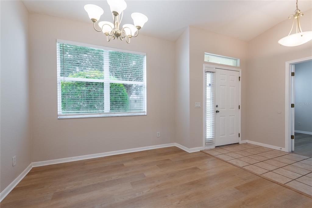A dining area features light wood-look flooring, a chandelier, a window, and a tiled entryway — 11112 HOLLY CONE DRIVE, RIVERVIEW, FL