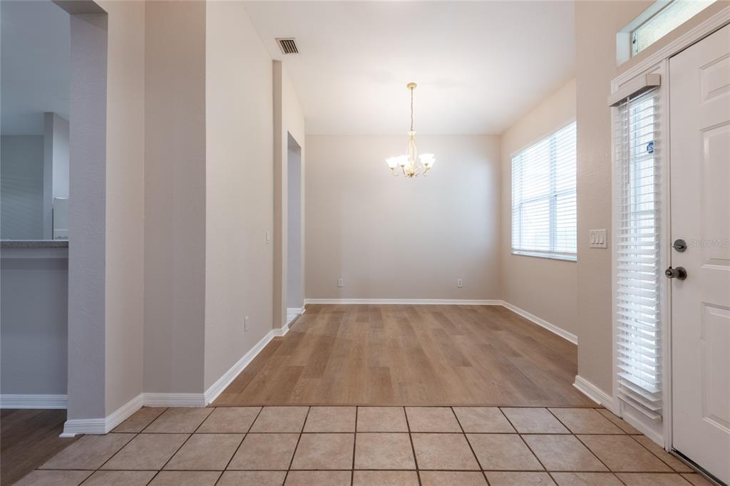 A dining area features wood-look flooring, a chandelier, and a white door with blinds — 11112 HOLLY CONE DRIVE, RIVERVIEW, FL
