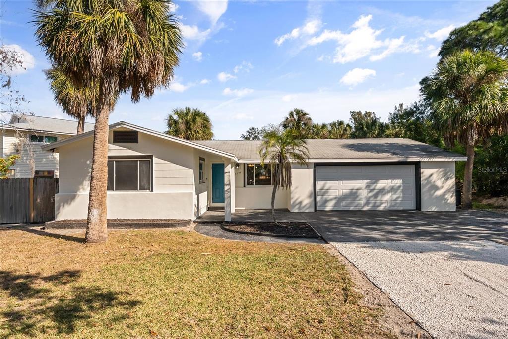 A single-story house with a white exterior, a two-car garage, and several palm trees — 10395 SAN MARTIN BOULEVARD NE, ST PETERSBURG, FL