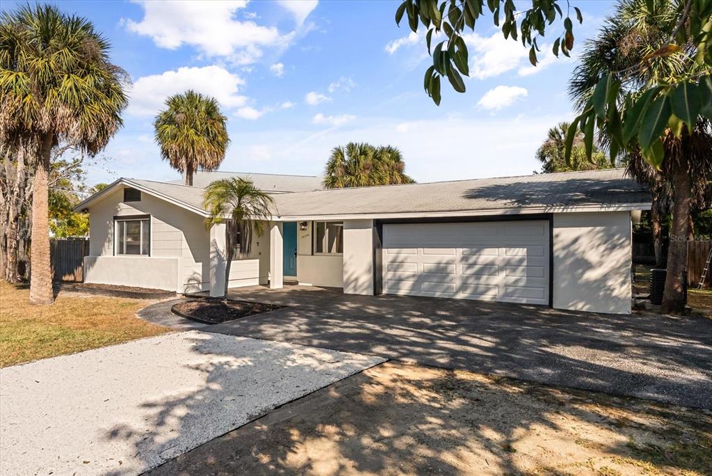 A single-story house with a white exterior, a two-car garage, and several palm trees — 10395 SAN MARTIN BOULEVARD NE, ST PETERSBURG, FL