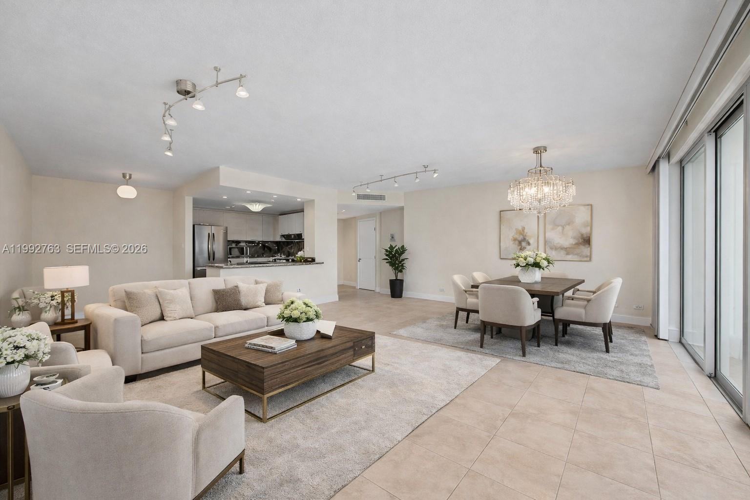 A bright, open-concept living and dining area features neutral furniture, tile flooring, and track lighting — 2451 Brickell Ave # 4F, Miami FL 33129, MIAMI, FL