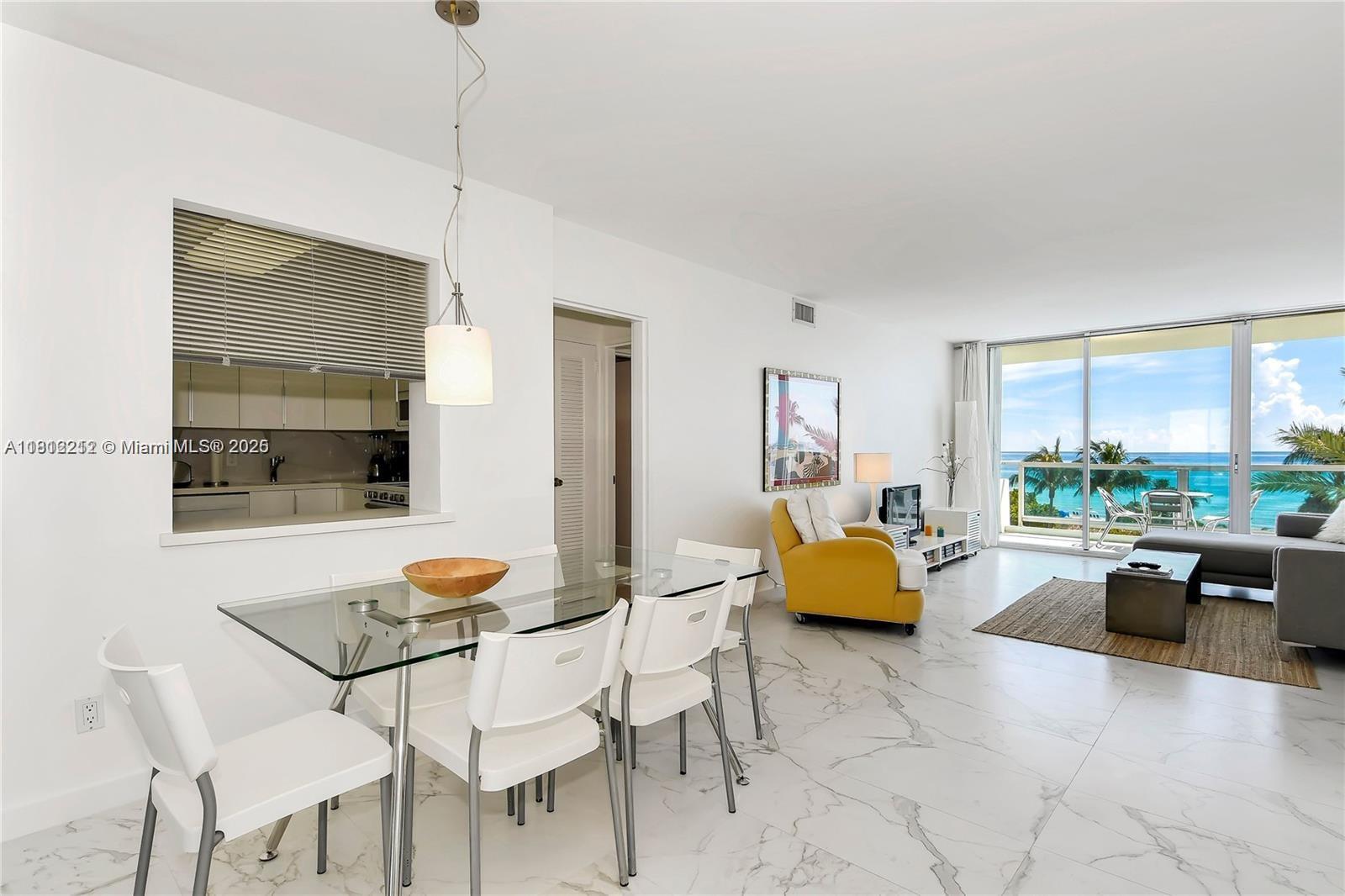A bright living and dining area features white marble floors and a balcony with ocean views — 5151 Collins Ave # 619, Miami Beach FL 33140, MIAMI BEACH, FL