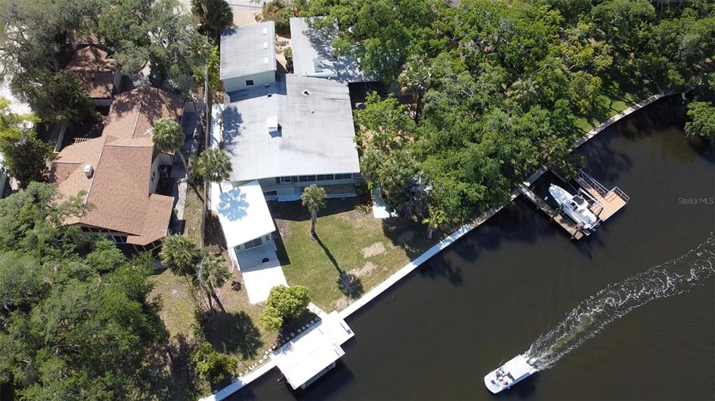 An aerial view shows a waterfront estate with multiple buildings, a boat dock, and river access — 7102 MANDY LANE, NEW PORT RICHEY, FL