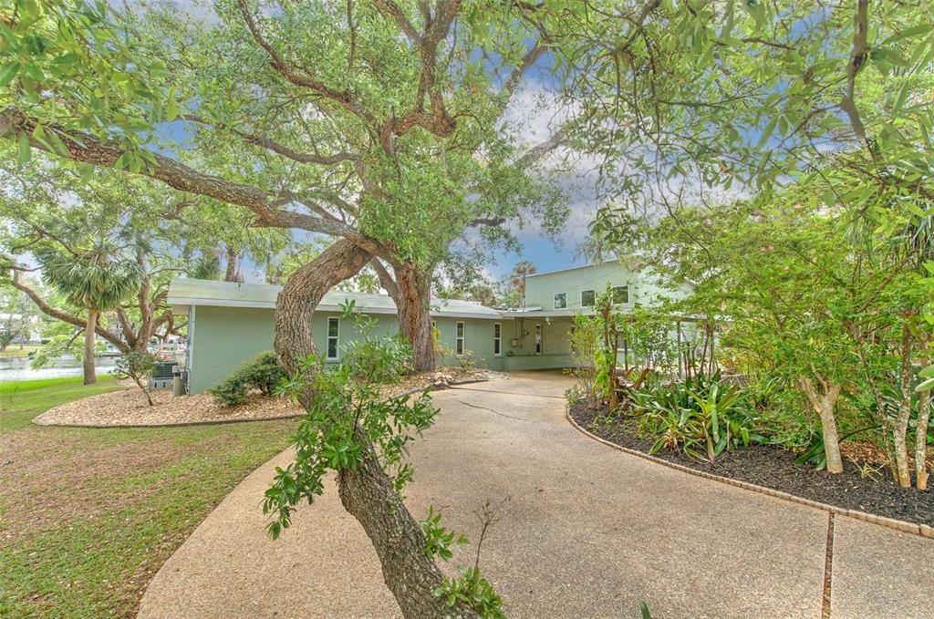 A covered entryway features a dark wood double door, gravel flooring, and stone stepping stones — 7102 MANDY LANE, NEW PORT RICHEY, FL