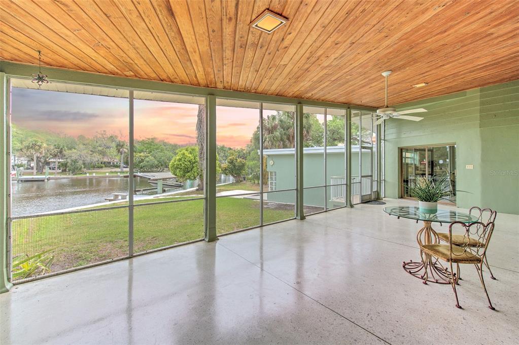 A garage with a concrete floor, wooden workbench, shelving, stairs, and two parked vintage cars — 7102 MANDY LANE, NEW PORT RICHEY, FL