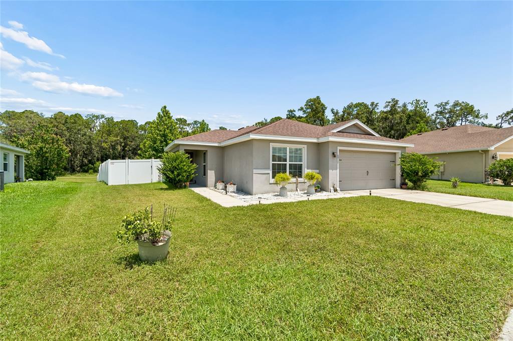 A single-story house with a beige exterior, a two-car garage, and a concrete driveway — 6917 GIDEON CIRCLE, ZEPHYRHILLS, FL