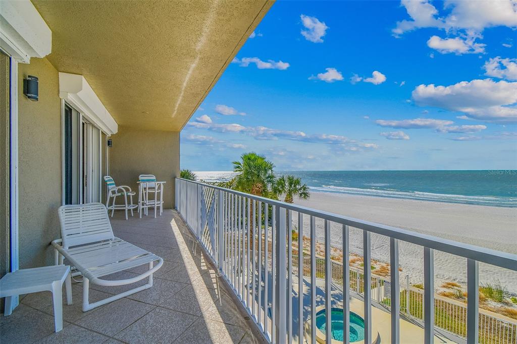 A balcony with white furniture overlooks a sandy beach and the ocean under a sky — 19710 GULF BOULEVARD UNIT 203, INDIAN SHORES, FL