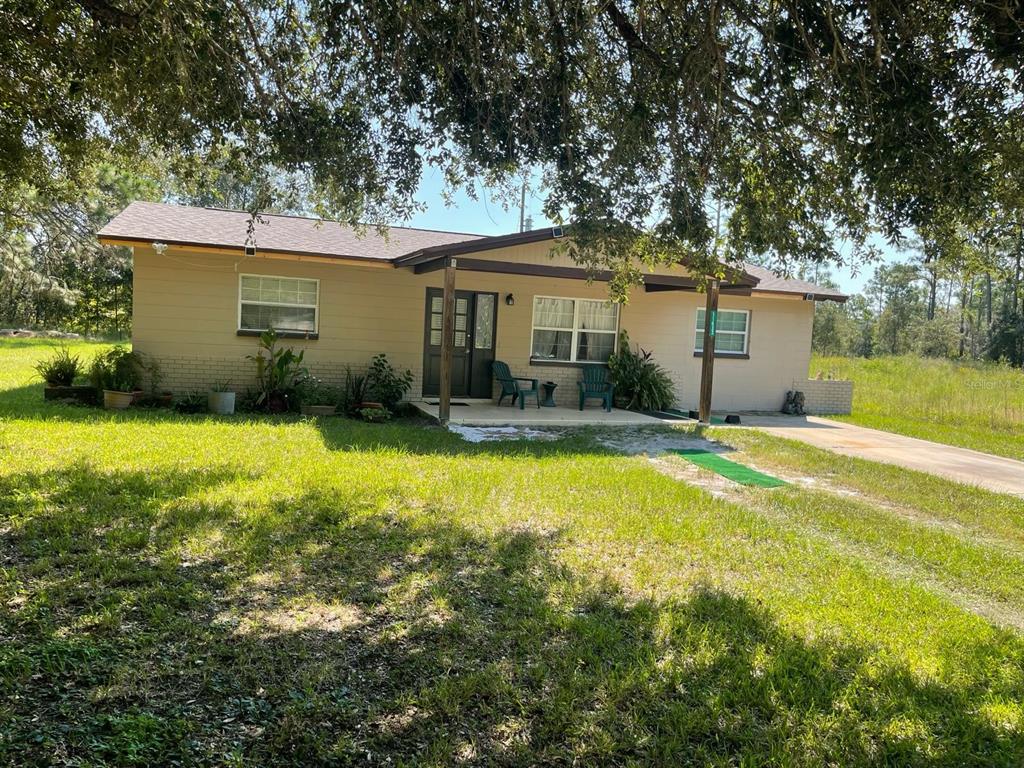A single-story tan house with a covered front porch sits on a grassy lot — 11433 S ROSEWATER POINT, HOMOSASSA, FL