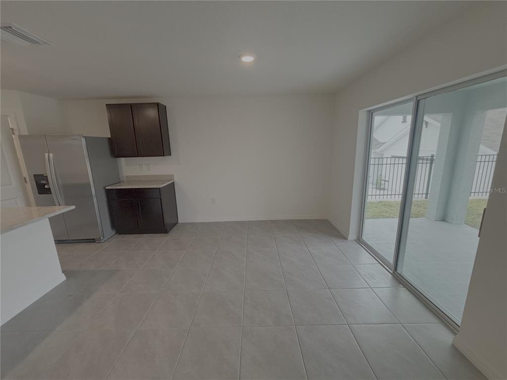 A kitchen and dining area with dark cabinets, stainless steel appliances, and sliding glass doors — 481 W REXFORD DRIVE, BEVERLY HILLS, FL