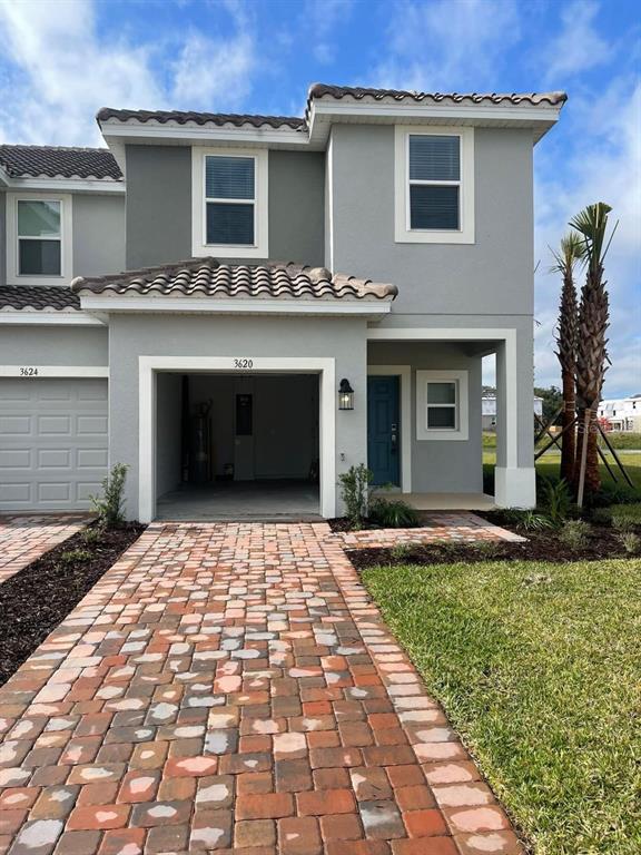 A two-story gray townhouse features a brick paver driveway and an open garage — 3620 LANDING NET DRIVE, KISSIMMEE, FL