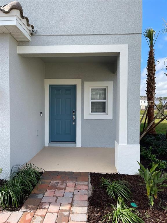 A blue front door and a single window are set within a covered entryway — 3620 LANDING NET DRIVE, KISSIMMEE, FL