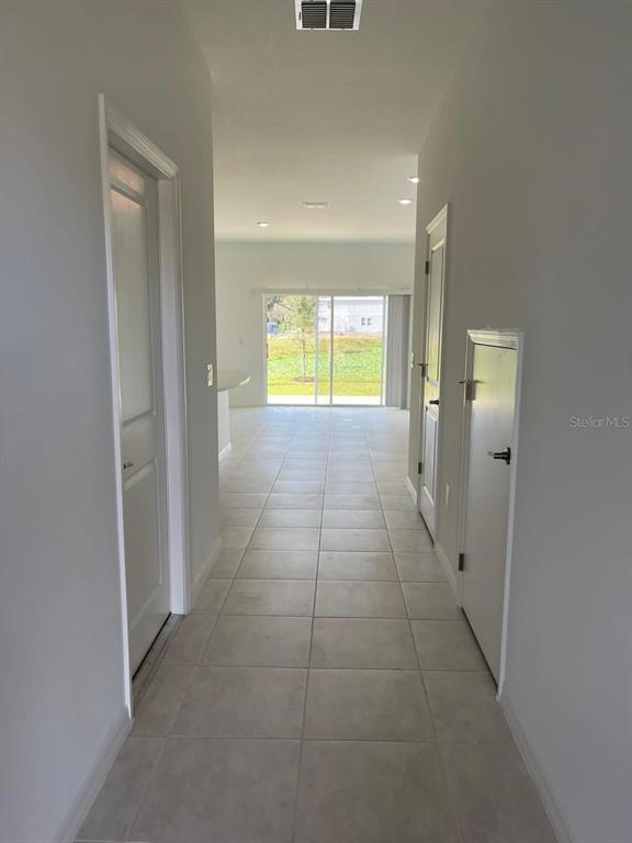 A tiled hallway leads toward a living area with a sliding glass door to the backyard — 3620 LANDING NET DRIVE, KISSIMMEE, FL