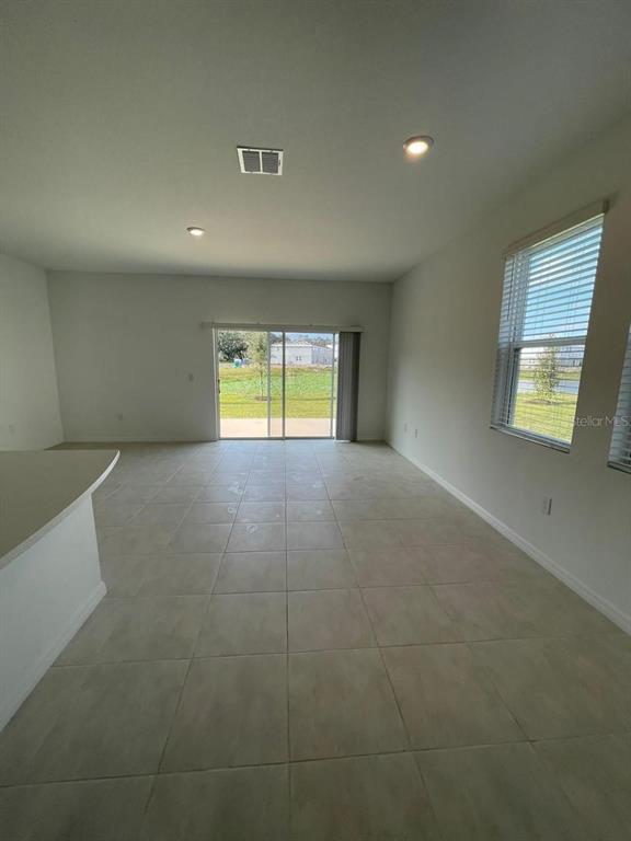An open-concept room features light-colored tile flooring, recessed lighting, and sliding glass doors — 3620 LANDING NET DRIVE, KISSIMMEE, FL