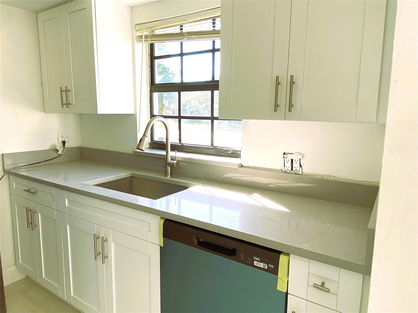 A kitchen with white cabinets, gray countertops, a stainless steel sink, and a dishwasher — 320 NW 4th Avenue # 1, Deerfield Beach FL 33441, DEERFIELD BEACH, FL