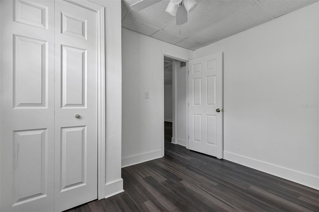 A room with dark wood-look flooring, white walls, a closet, and a doorway — 2027 30TH AVENUE N Bottom unit, ST PETERSBURG, FL