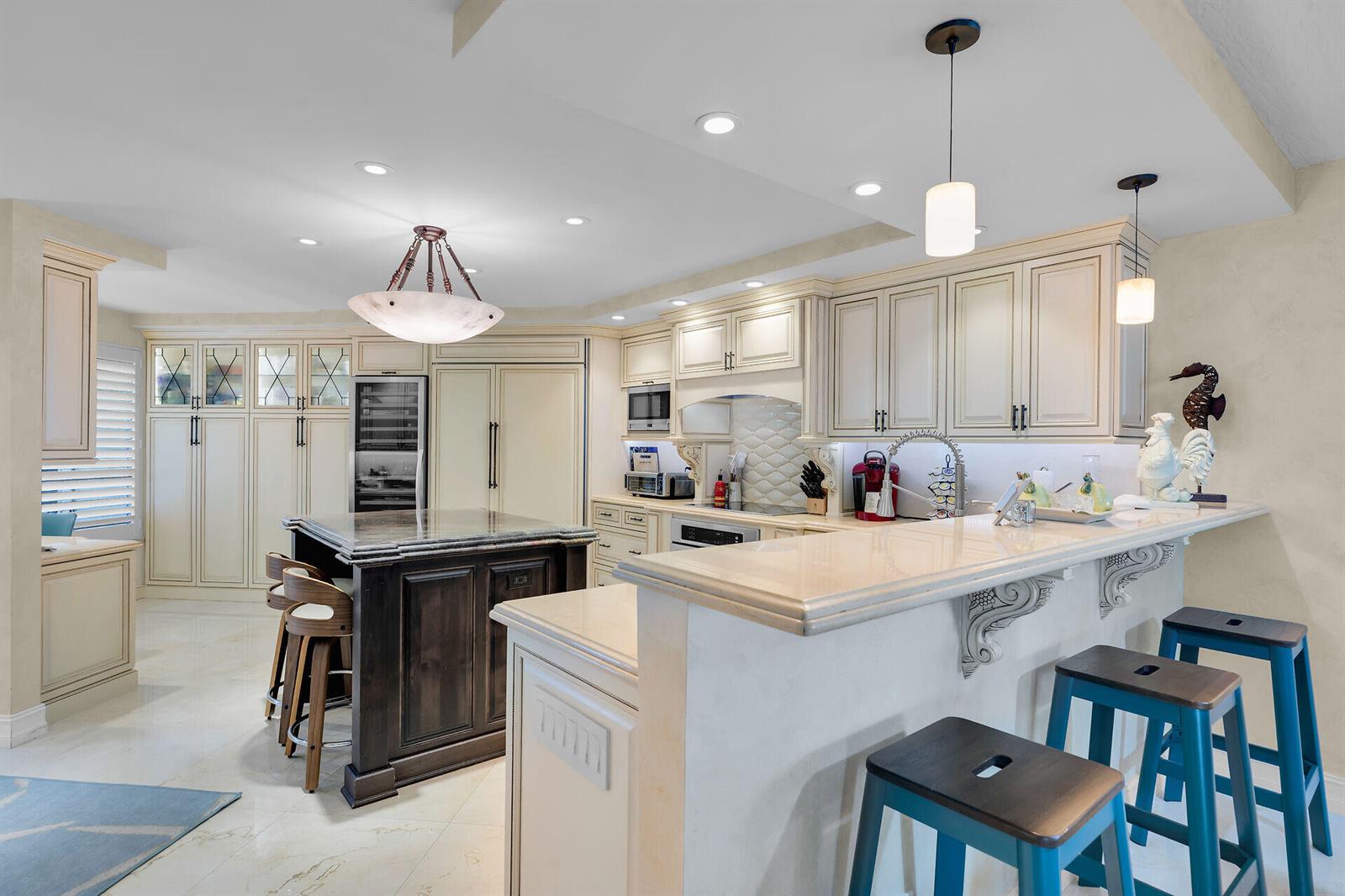 A kitchen features cream cabinetry, a dark wood island, and a raised breakfast bar — 87851 Old Highway # M5, Islamorada FL 33036, ISLAMORADA, FL