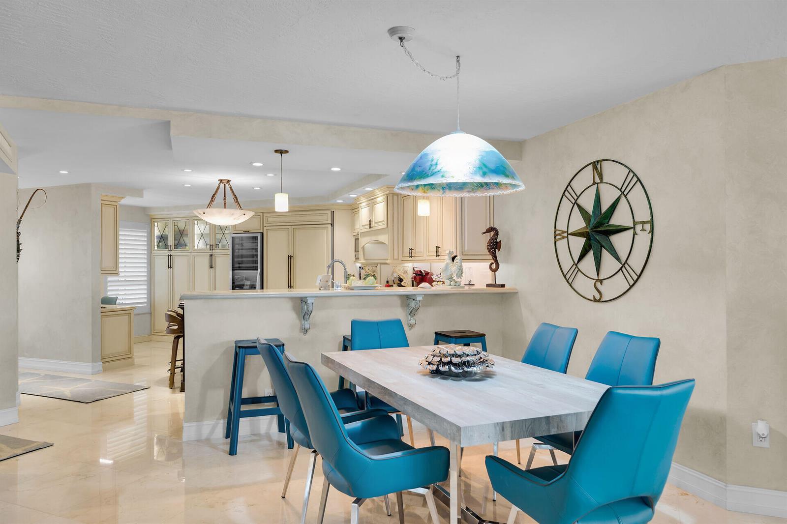 A dining area with a light wood table and blue chairs sits before a kitchen — 87851 Old Highway # M5, Islamorada FL 33036, ISLAMORADA, FL