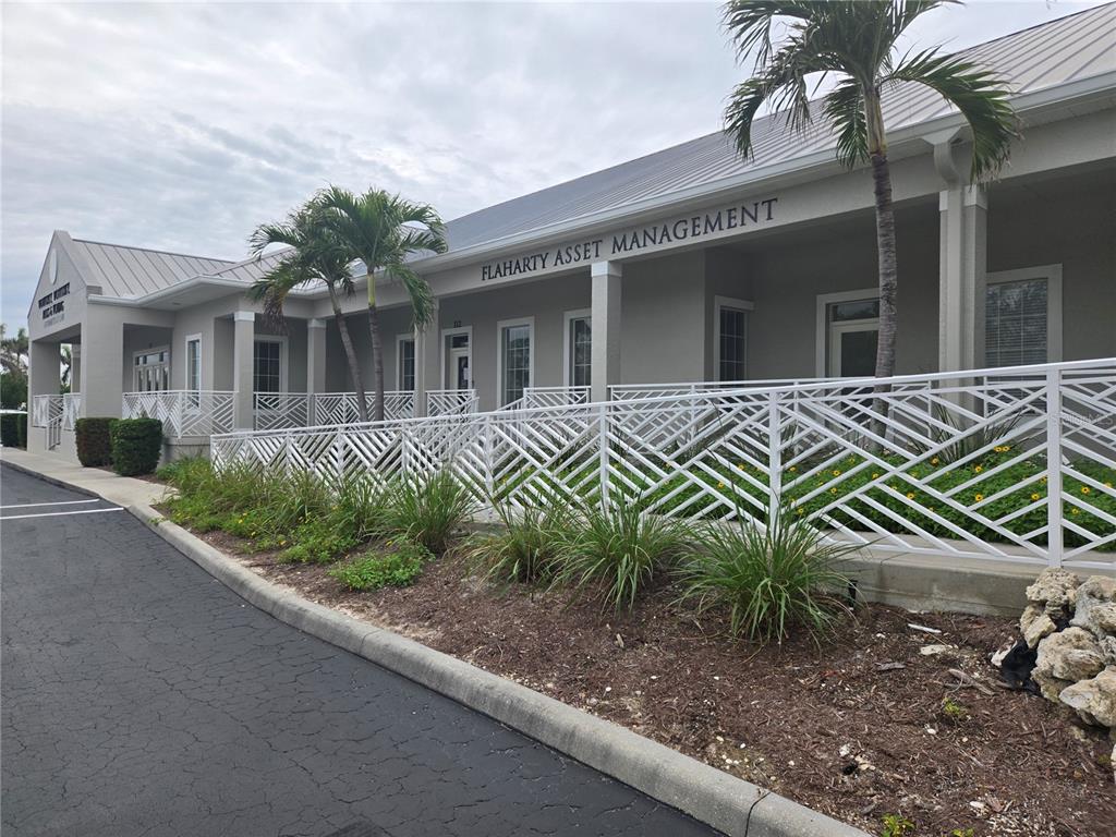 The exterior of a commercial building features a white decorative railing and palm trees — 1107 W MARION AVENUE, PUNTA GORDA, FL