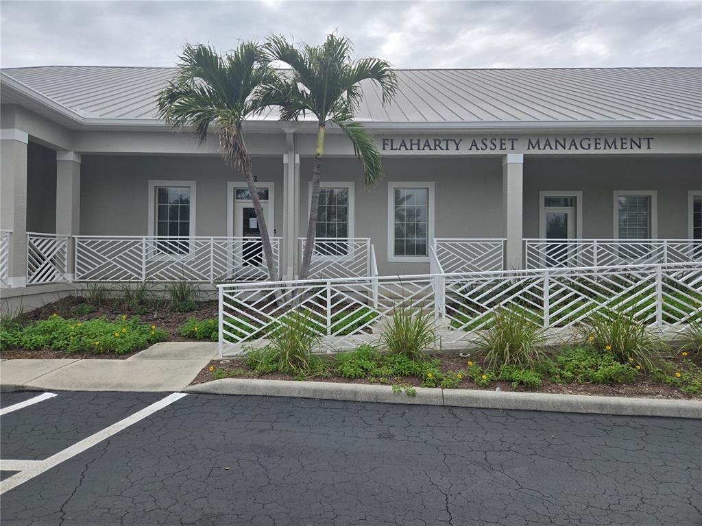 The exterior of a single-story commercial building features a white railing, palm trees, and signage — 1107 W MARION AVENUE, PUNTA GORDA, FL