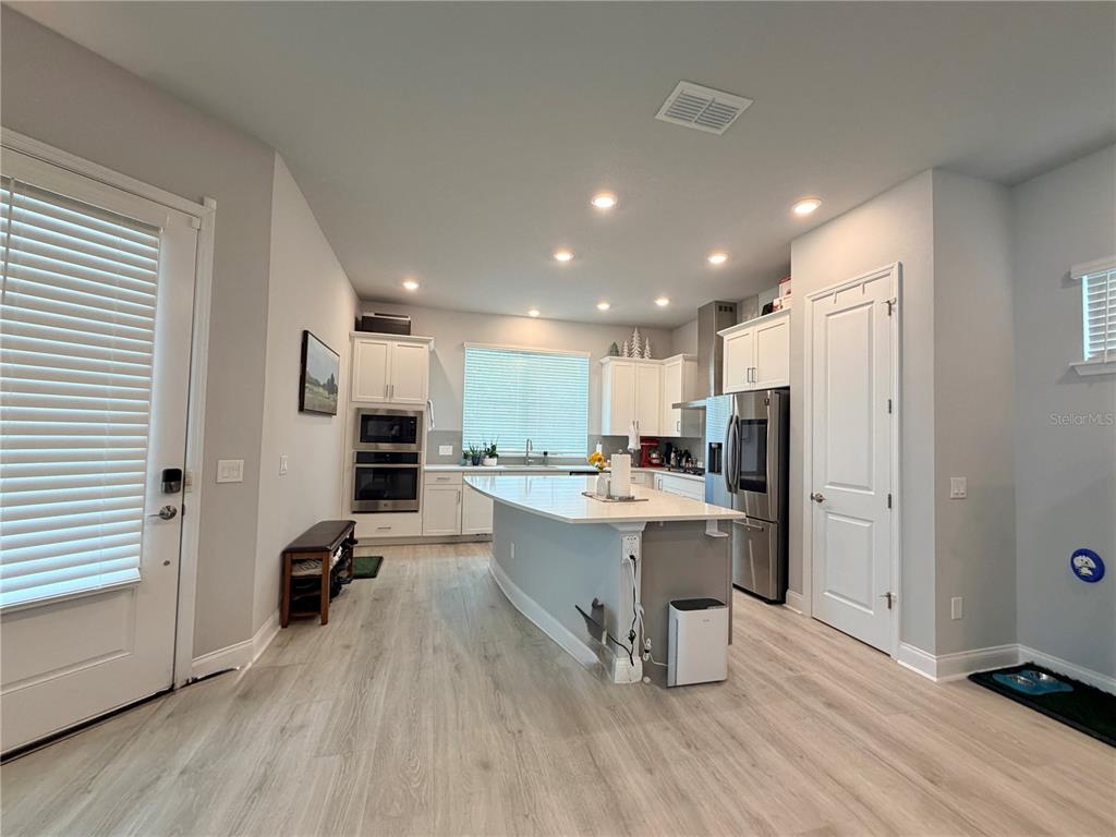 A modern kitchen features white cabinetry, stainless steel appliances, a central island, and light flooring — 660 ROSEWOOD WAY, LAKE MARY, FL