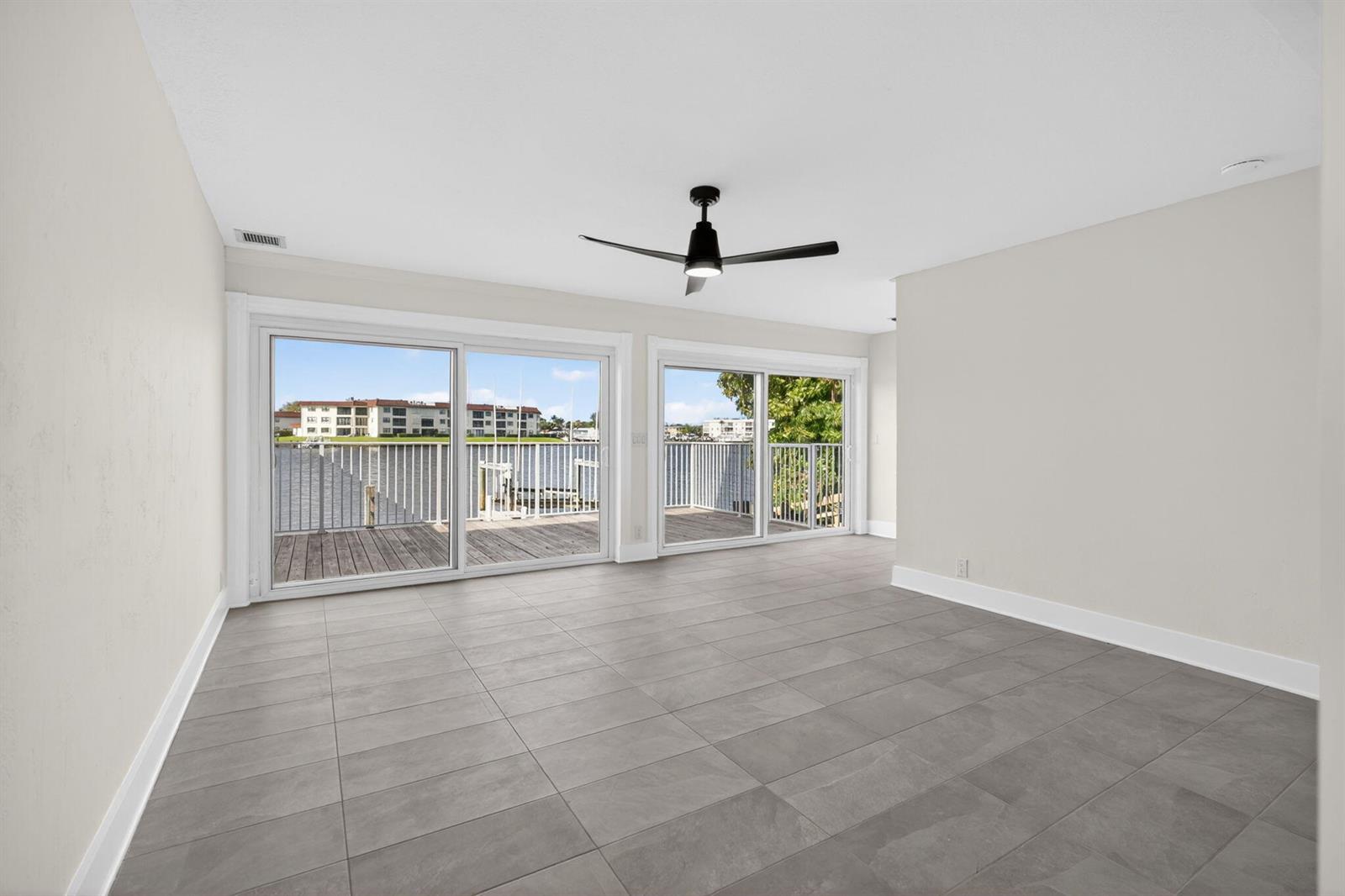 An empty room with gray tile flooring, a ceiling fan, and sliding doors to a deck — 624 Southwind Circle # 3, North Palm Beach FL 33408, NORTH PALM BEACH, FL