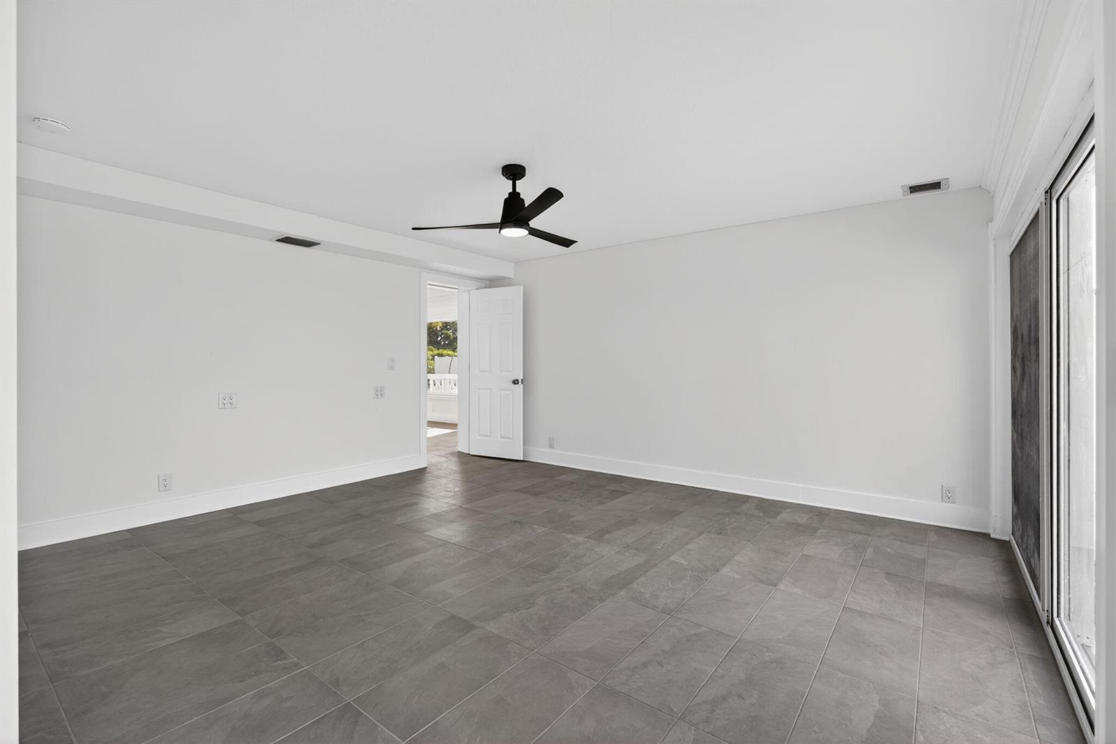 An empty room features white walls, gray tile flooring, a ceiling fan, and sliding doors — 624 Southwind Circle # 3, North Palm Beach FL 33408, NORTH PALM BEACH, FL
