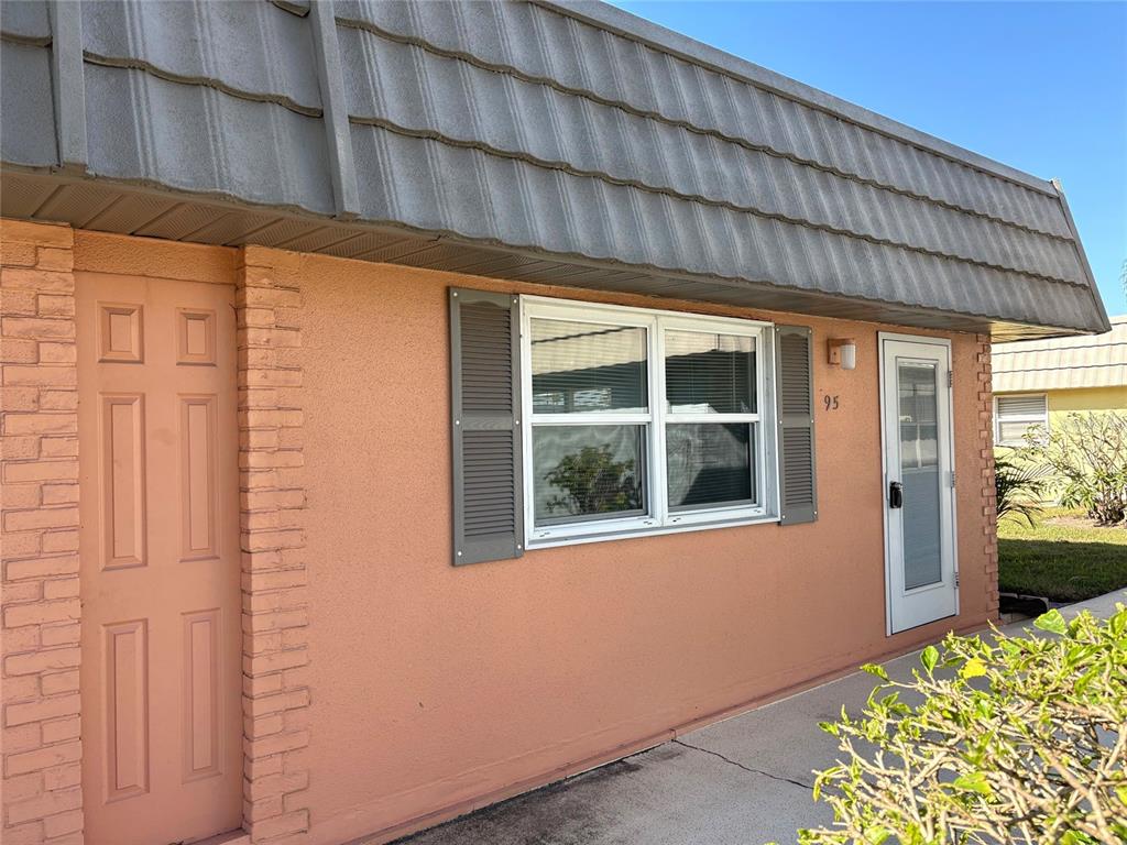 The exterior of a peach-colored building features a gray mansard roof and a white door — 201 BEDFORD STREET UNIT 95, SUN CITY CENTER, FL