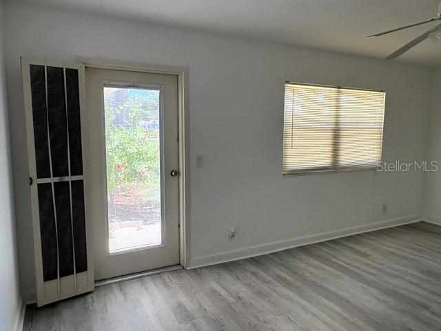 A room with light wood-look flooring, a glass-paneled door, and a window with blinds — 201 BEDFORD STREET UNIT 95, SUN CITY CENTER, FL
