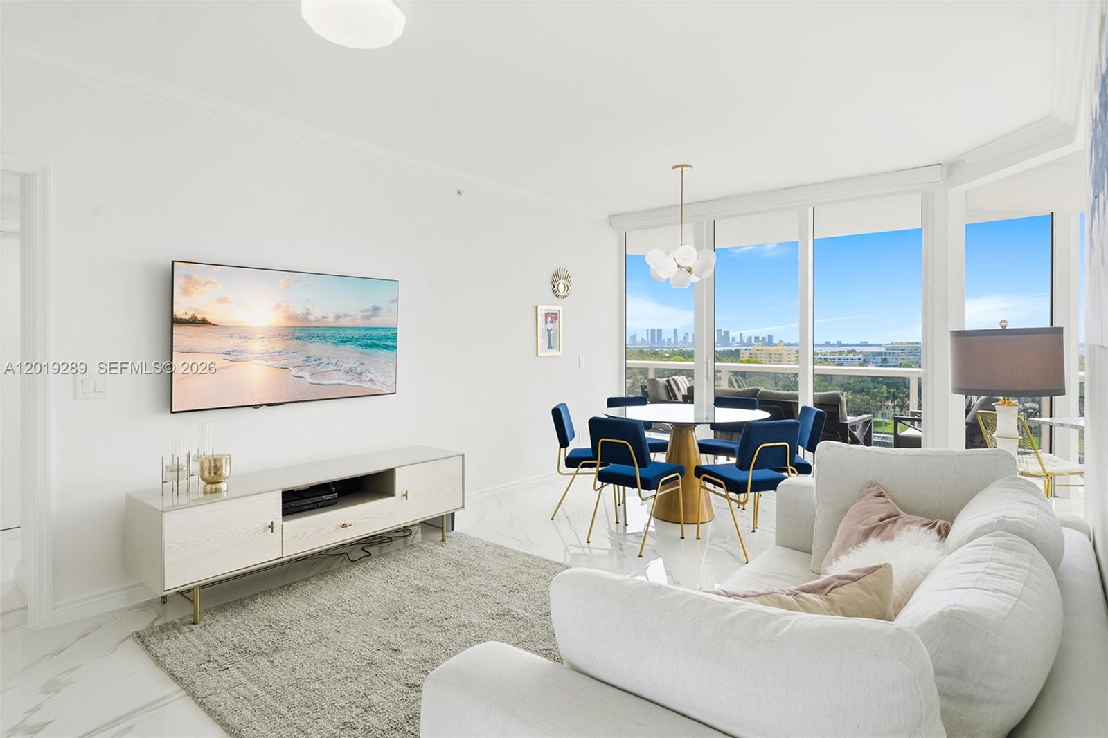 A living and dining area features white marble floors, a wall-mounted television, and floor-to-ceiling windows — 4779 Collins Ave # 1206, Miami Beach FL 33140, MIAMI BEACH, FL