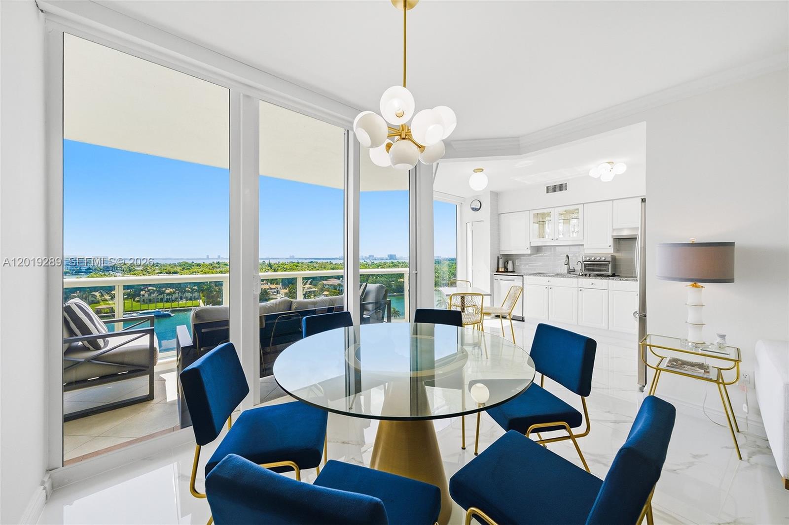A dining area features a glass table, blue chairs, and a balcony with water views — 4779 Collins Ave # 1206, Miami Beach FL 33140, MIAMI BEACH, FL