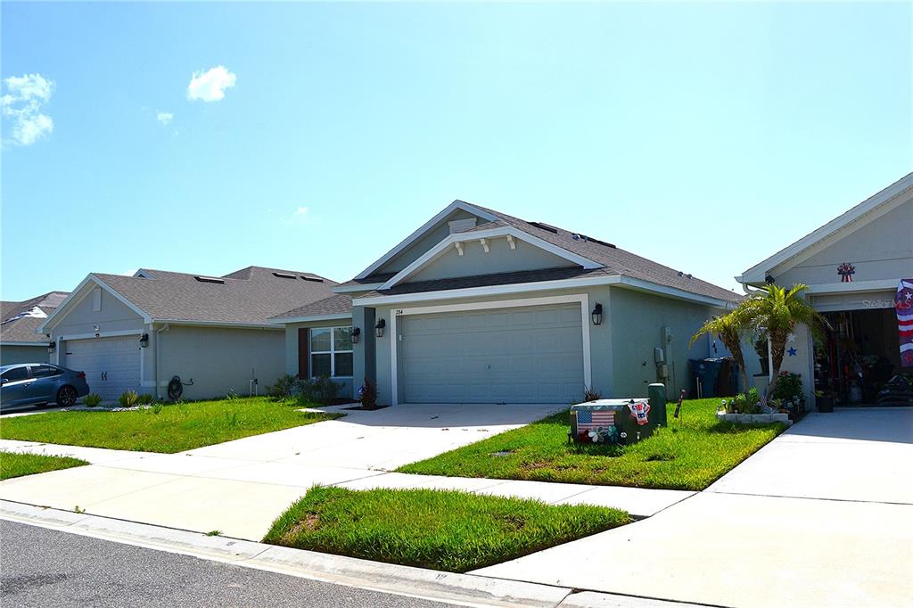 A suburban house with a light-colored exterior, a two-car garage, and a concrete driveway — 284 CITRUS POINTE DRIVE, HAINES CITY, FL