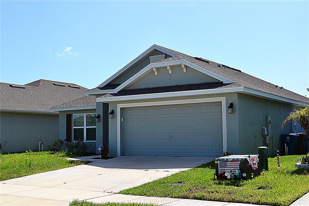 A single-story house with a gray stucco exterior, a two-car garage, and a concrete driveway — 284 CITRUS POINTE DRIVE, HAINES CITY, FL