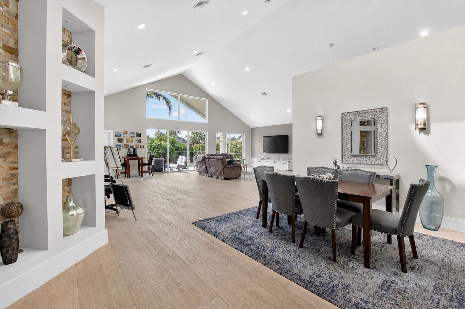 A spacious open-concept living and dining area features vaulted ceilings, tile floors, and large windows — 17320 Loch Lomond Way, Boca Raton FL 33496, BOCA RATON, FL