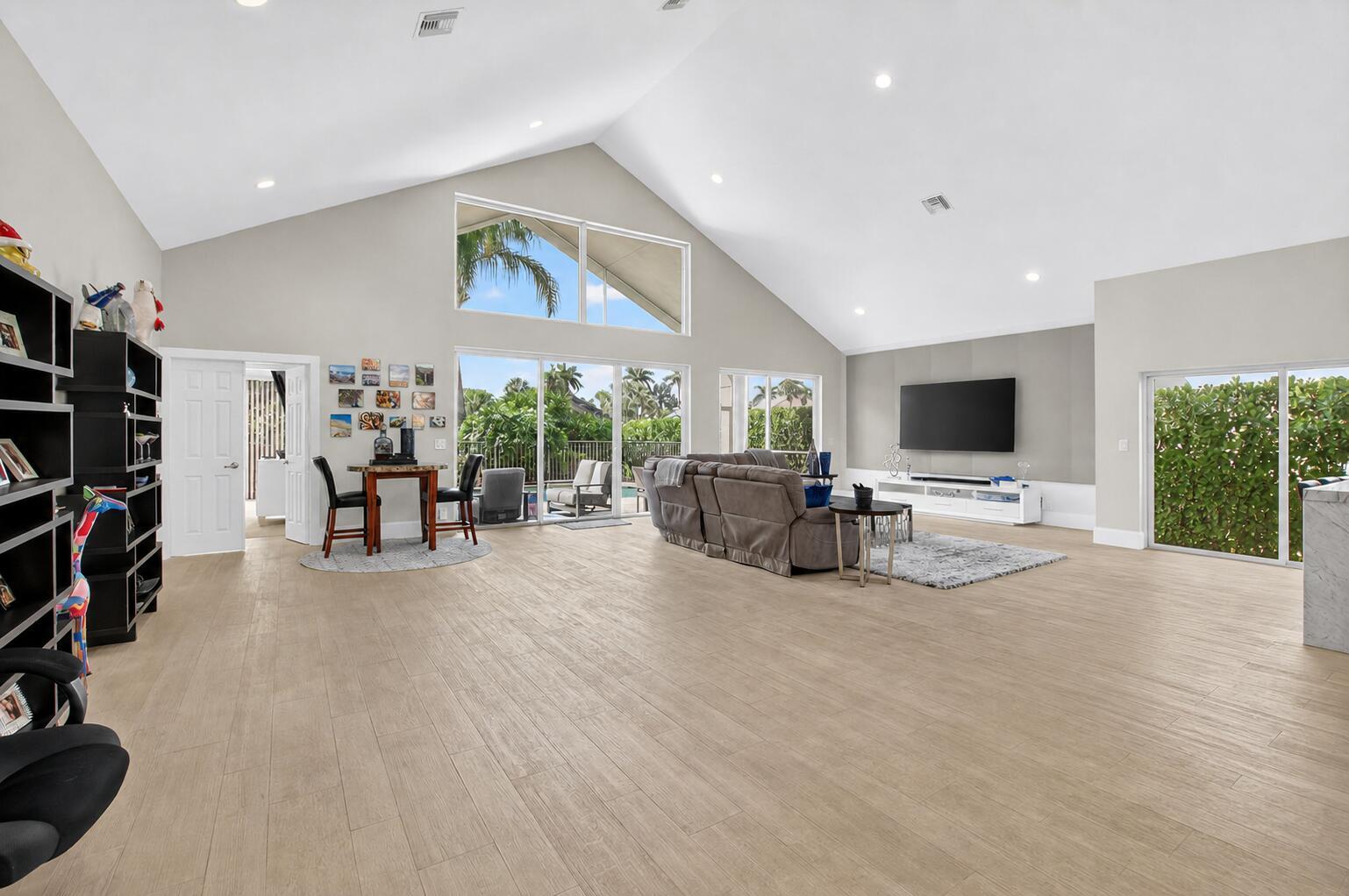 A spacious living room features vaulted ceilings, light wood-look flooring, and large sliding glass doors — 17320 Loch Lomond Way, Boca Raton FL 33496, BOCA RATON, FL