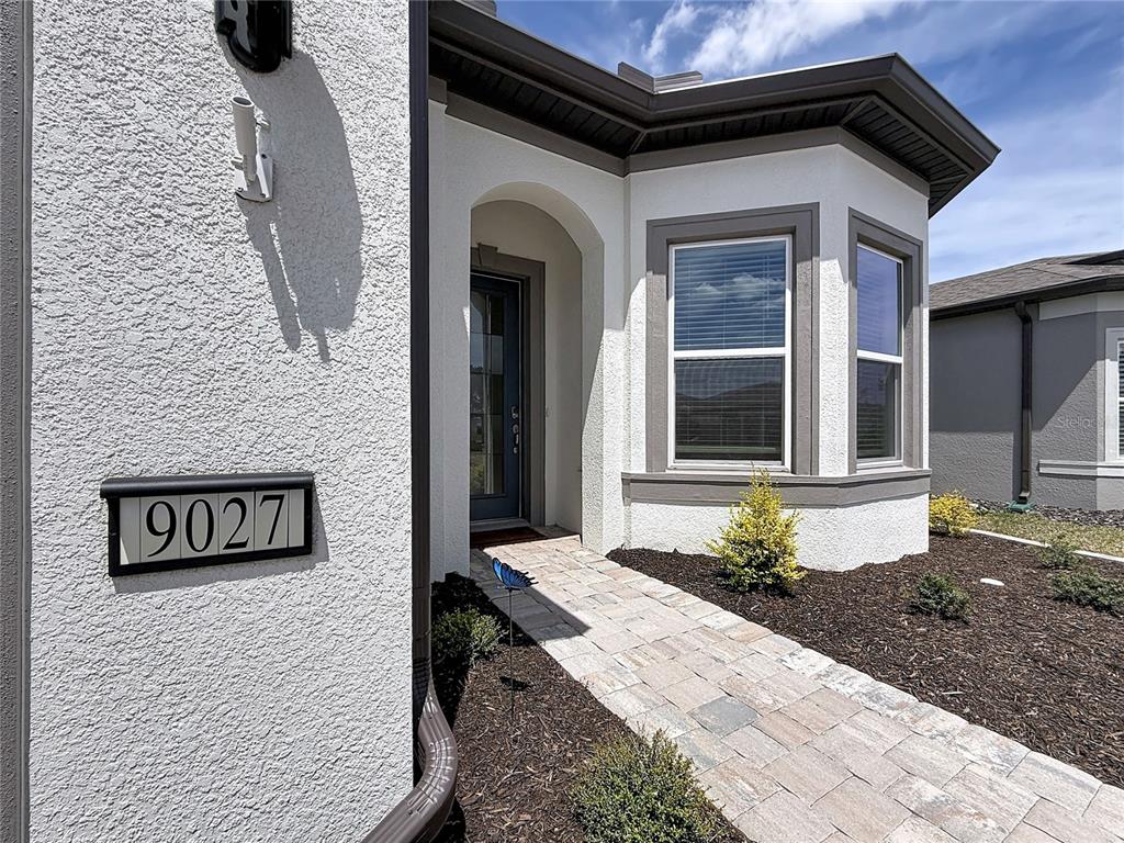 The exterior of a house features a stone walkway leading to a recessed front door — 9027 SW 52ND PLACE ROAD, OCALA, FL