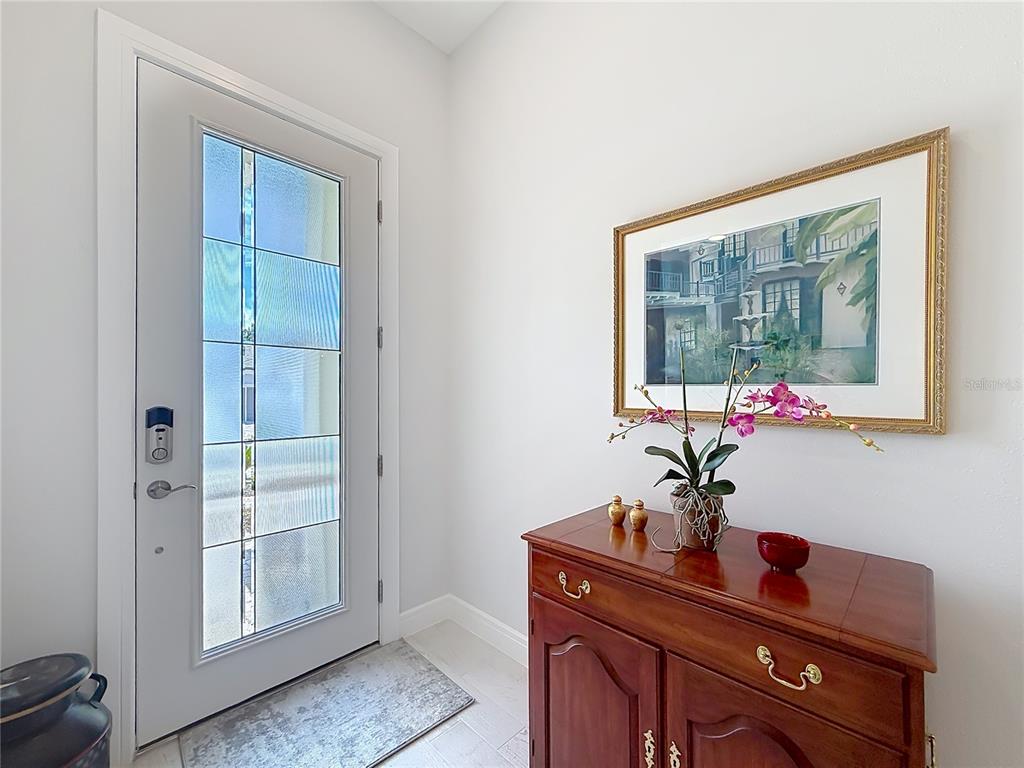 A bright entryway features a glass-paneled front door, a wooden cabinet, and framed wall art — 9027 SW 52ND PLACE ROAD, OCALA, FL