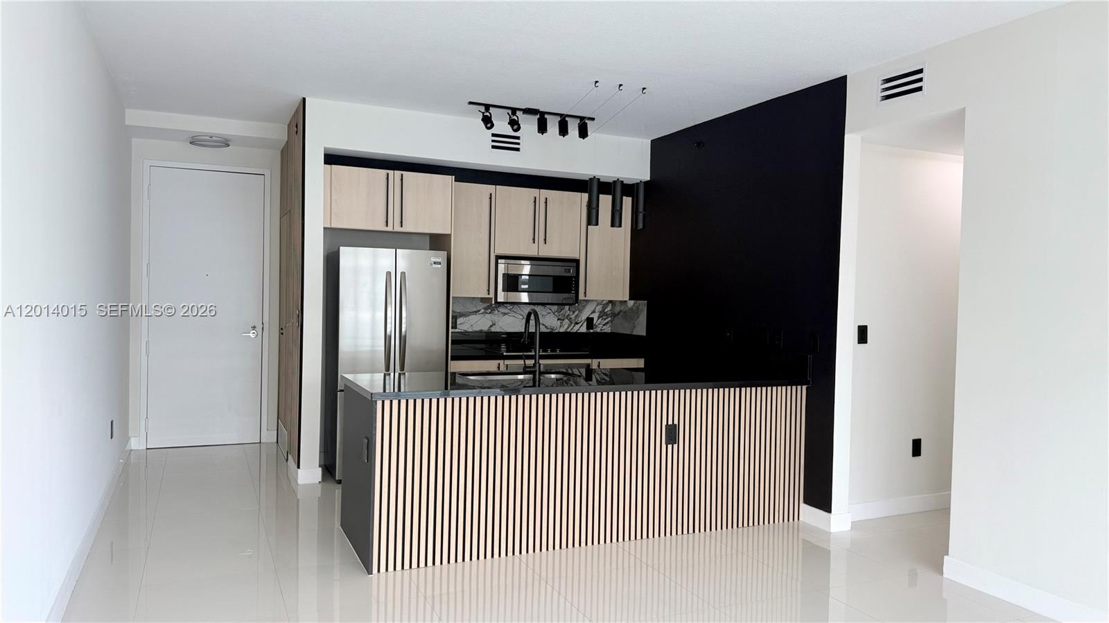 A modern kitchen features light wood cabinets, a black accent wall, and a slatted island — 79 SW 12th St # 4008S, Miami FL 33130, MIAMI, FL