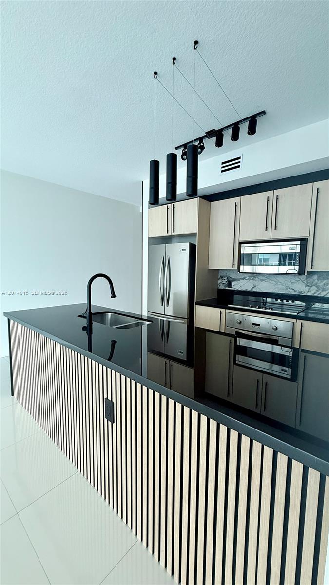 A modern kitchen features a slatted wood island, black countertops, and stainless steel appliances — 79 SW 12th St # 4008S, Miami FL 33130, MIAMI, FL