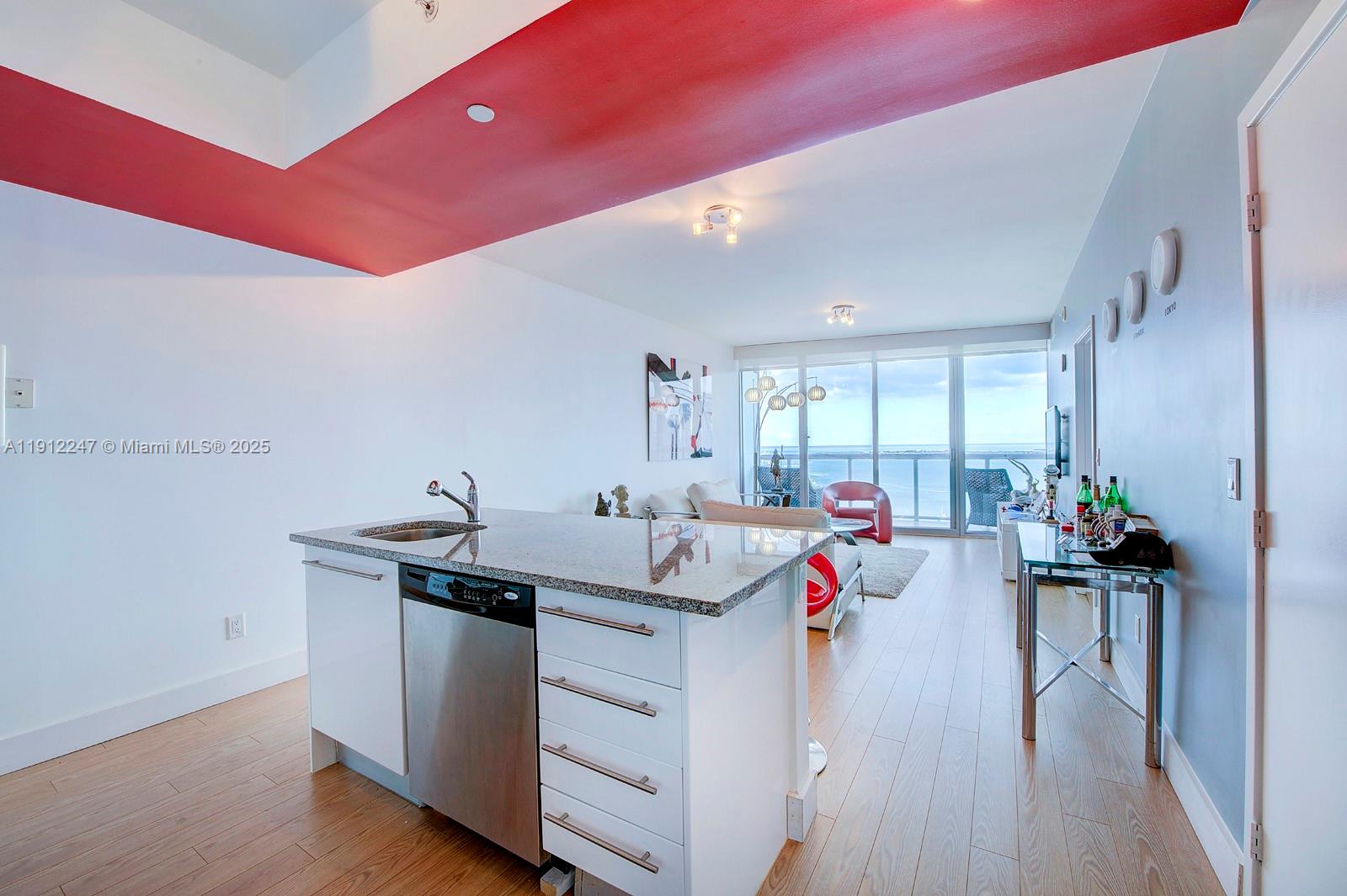 A kitchen island with a stainless steel dishwasher sits in an open-concept living area — 888 Biscayne Blvd # 4007, Miami FL 33132, MIAMI, FL