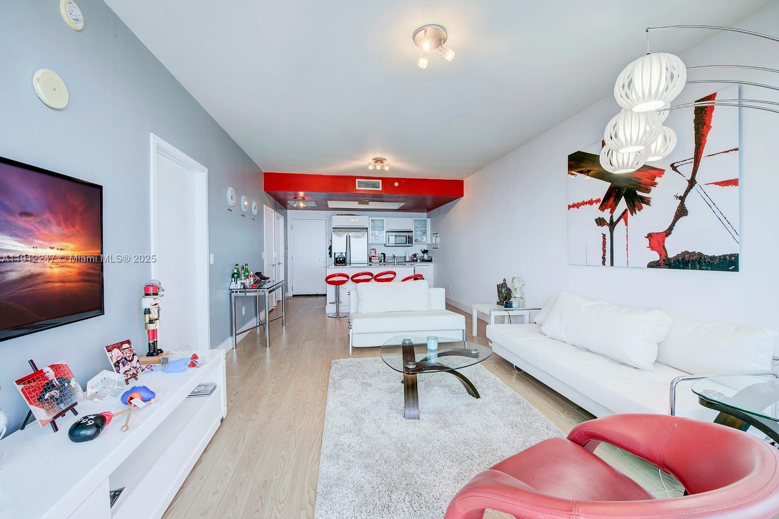 A living room features white sofas, a red accent wall, and a kitchen area — 888 Biscayne Blvd # 4007, Miami FL 33132, MIAMI, FL