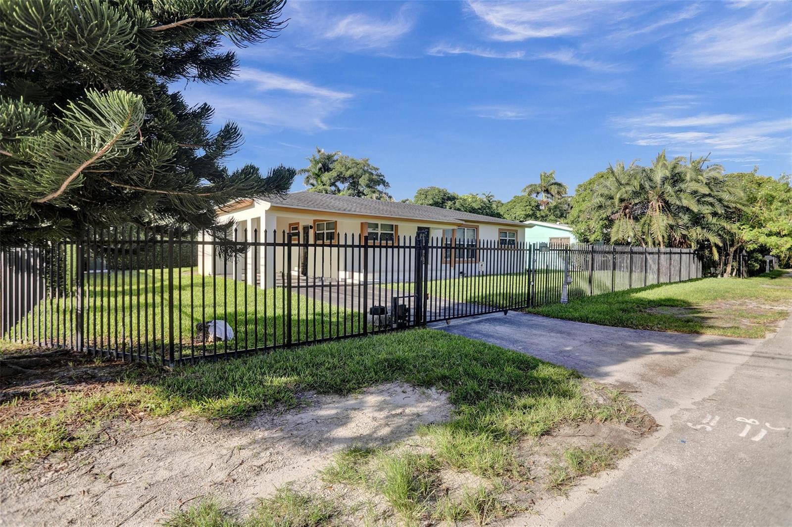 A single-story house with a fenced yard and a paved driveway under a blue sky — 30 NE 139th Street, Miami FL 33161, MIAMI, FL