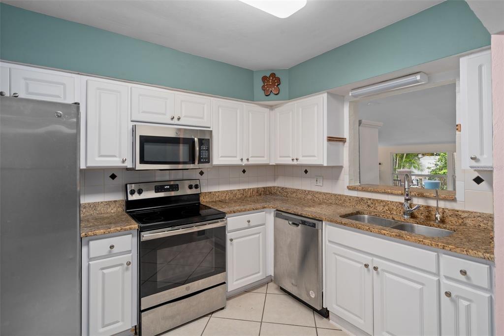 A kitchen with white cabinets, stainless steel appliances, and granite countertops — 9812 51ST AVENUE N, ST PETERSBURG, FL