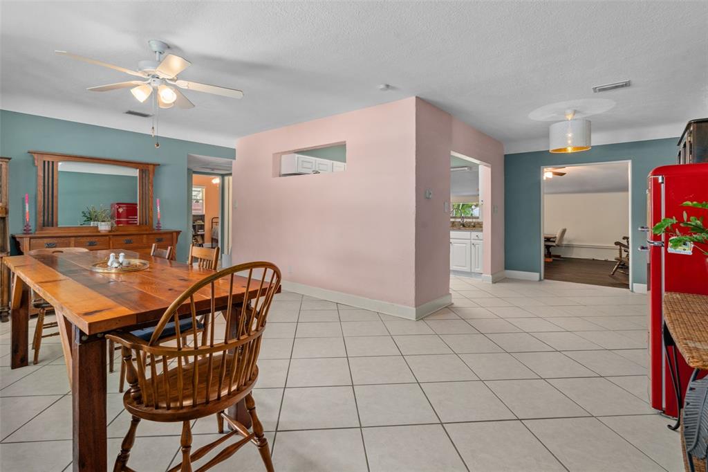 A dining room with a wooden table, tile flooring, and a central pink accent wall — 9812 51ST AVENUE N, ST PETERSBURG, FL