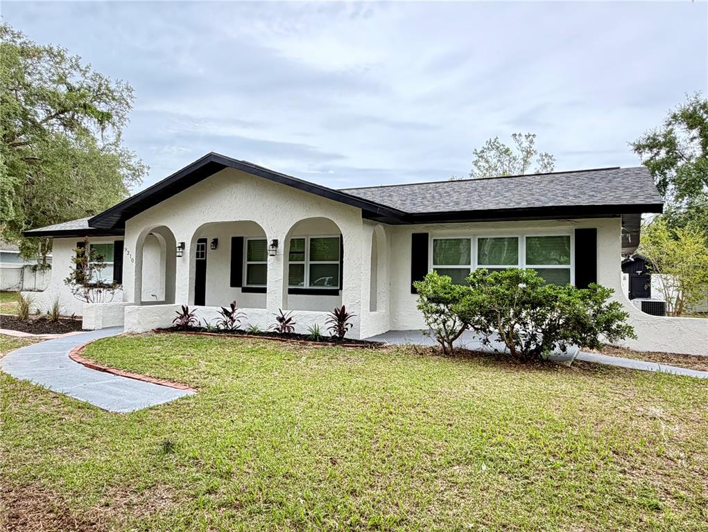 A single-story house with white stucco walls, black trim, and an arched front porch — 9310 SE 164TH PLACE, SUMMERFIELD, FL