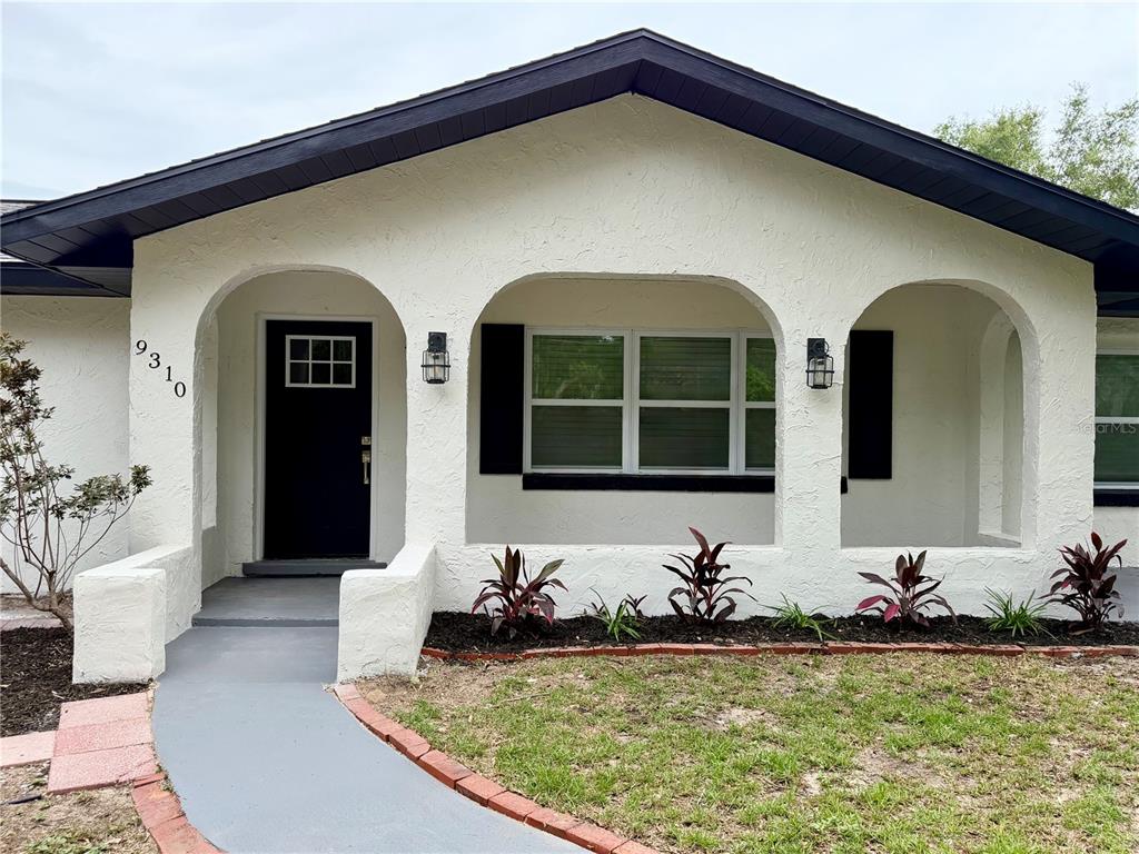 A white stucco house features a covered front porch with three arched openings — 9310 SE 164TH PLACE, SUMMERFIELD, FL