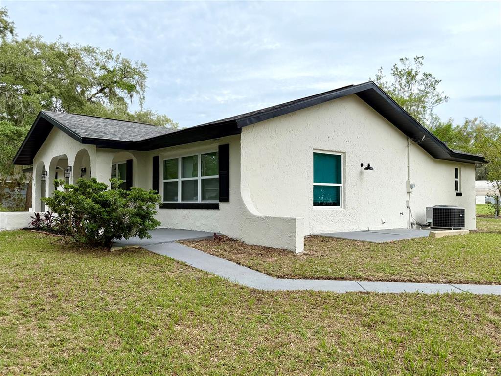 A single-story house with white stucco walls, a dark roof, and a front walkway — 9310 SE 164TH PLACE, SUMMERFIELD, FL