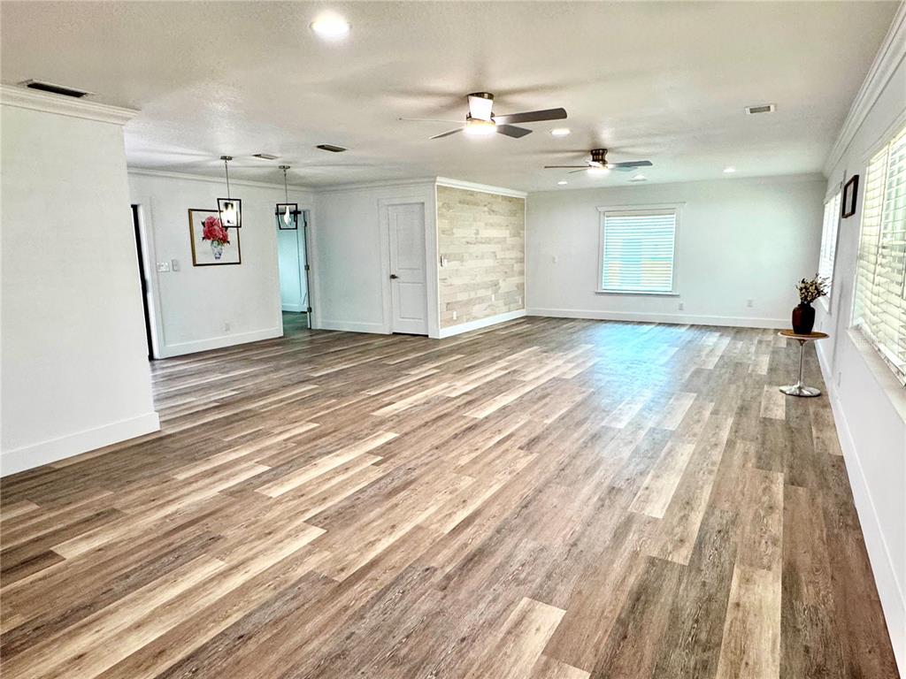 A spacious living area features light wood-look flooring, white walls, and a wood-plank accent wall — 9310 SE 164TH PLACE, SUMMERFIELD, FL
