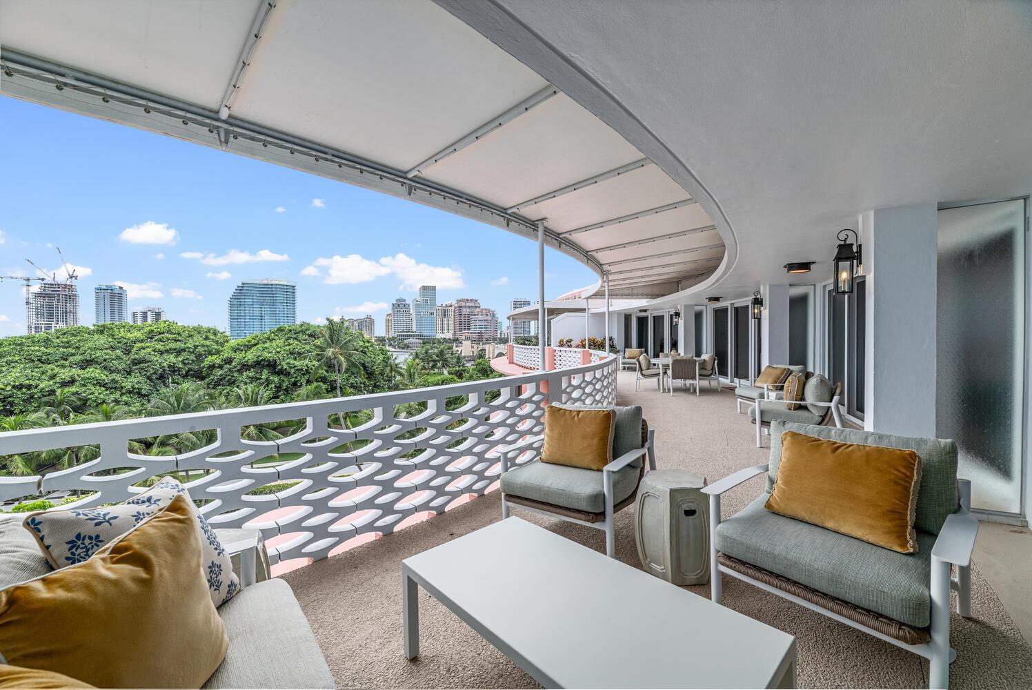 A curved balcony features outdoor seating, a white patterned railing, and views of a city skyline — 315 S Lake Drive # C, Palm Beach FL 33480, PALM BEACH, FL