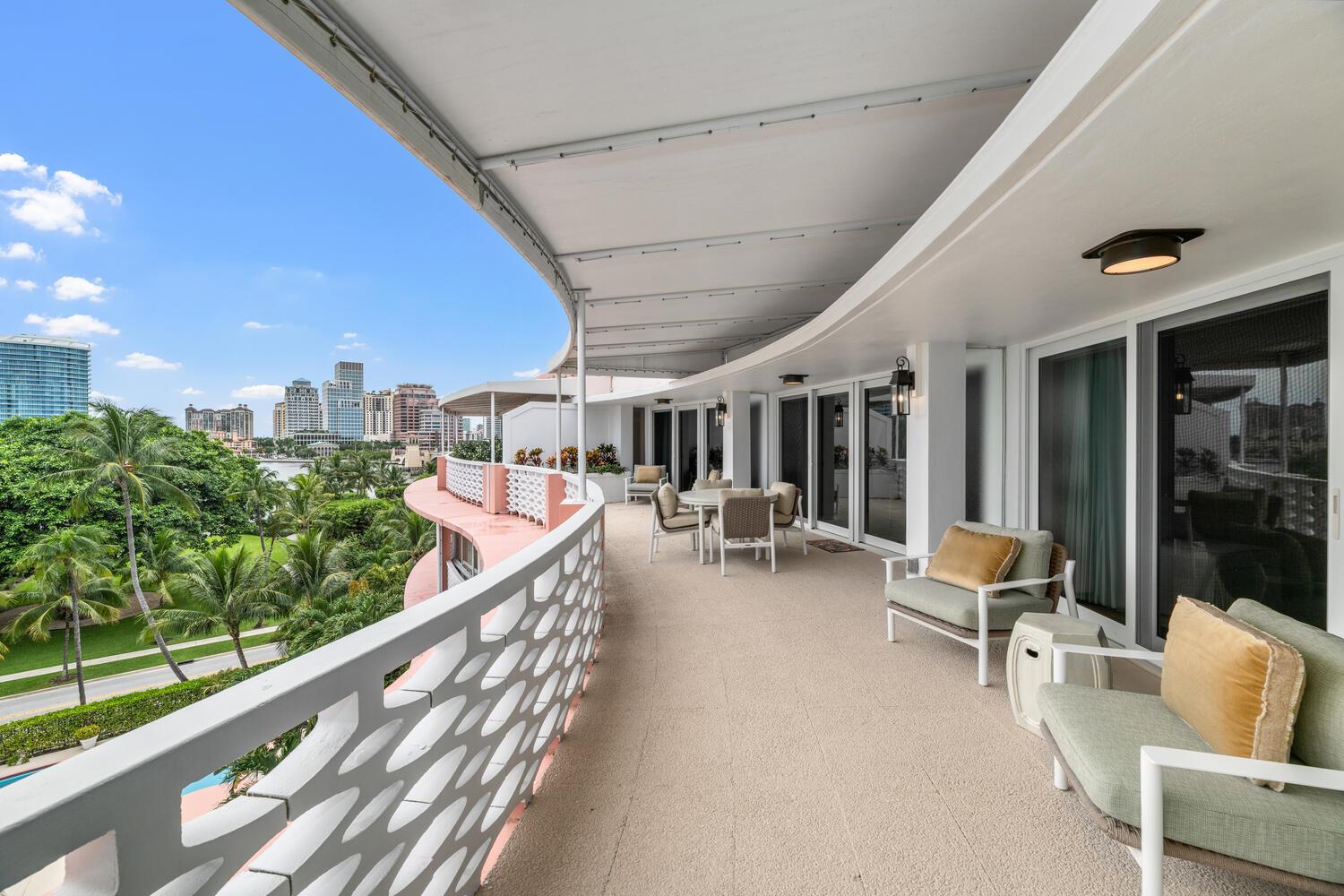 A curved balcony features outdoor seating, a patterned white railing, and views of a city skyline — 315 S Lake Drive # C, Palm Beach FL 33480, PALM BEACH, FL